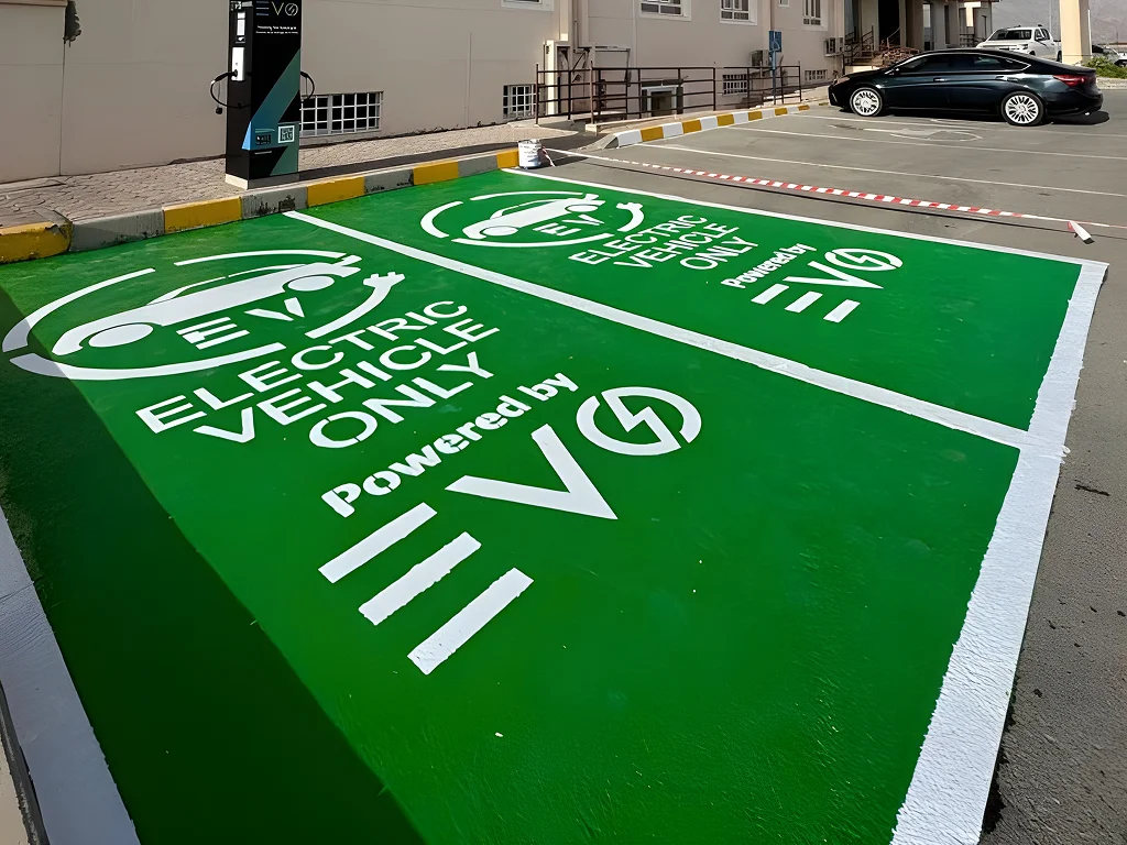 Green charging spot with large 'Electric Vehicle Only' text and EV symbol, indicating a designated EV parking area in a lot